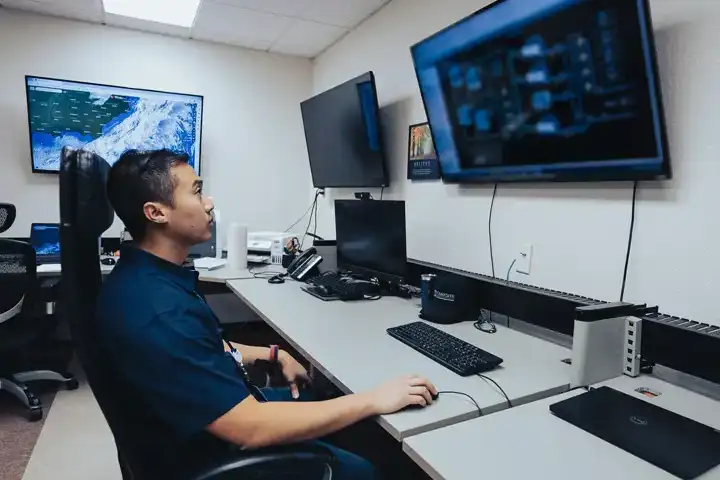 A photograph of a data center security professional monitoring video surveillance cameras.